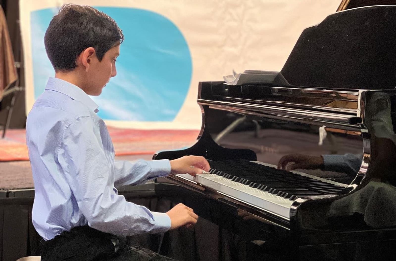An ABA Music Academy student at the grand piano during a summer lesson