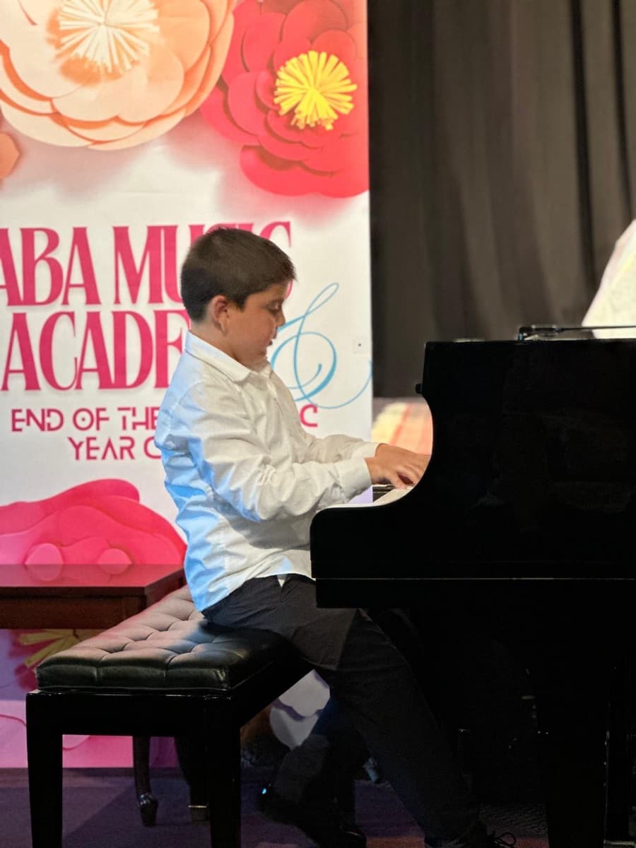 A school-age student performing at the grand piano at the June 2026 concert