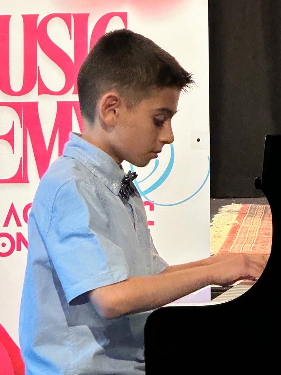 A student concentrating at the keys, hands in position, during a recital