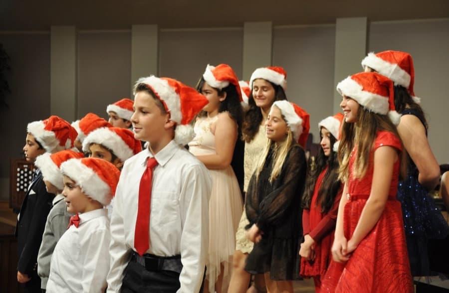 Students laughing together in Santa hats at the holiday recital